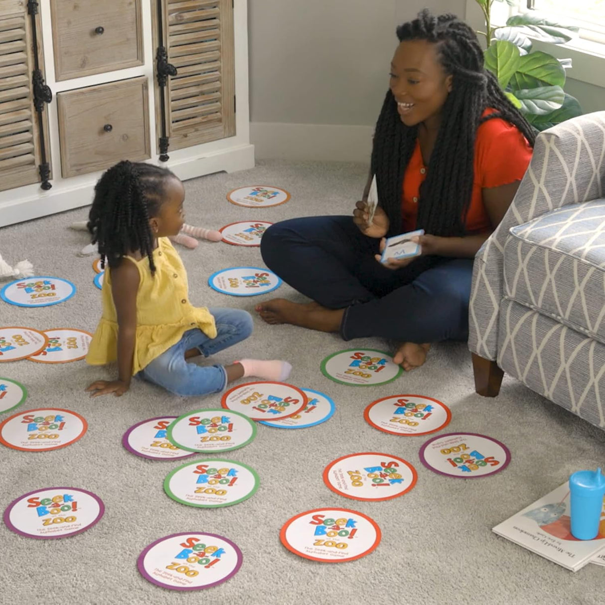 Mother and child play the educational matching game Seek a Boo at the Zoo with colorful animal cards on the floor.