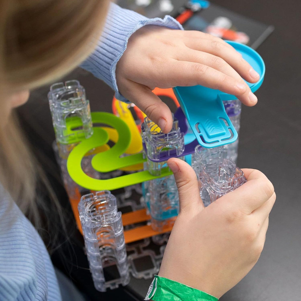 Child assembling colorful hollow stacking cubes and tracks in the Trestle Tracks Deluxe Set marble run toy.