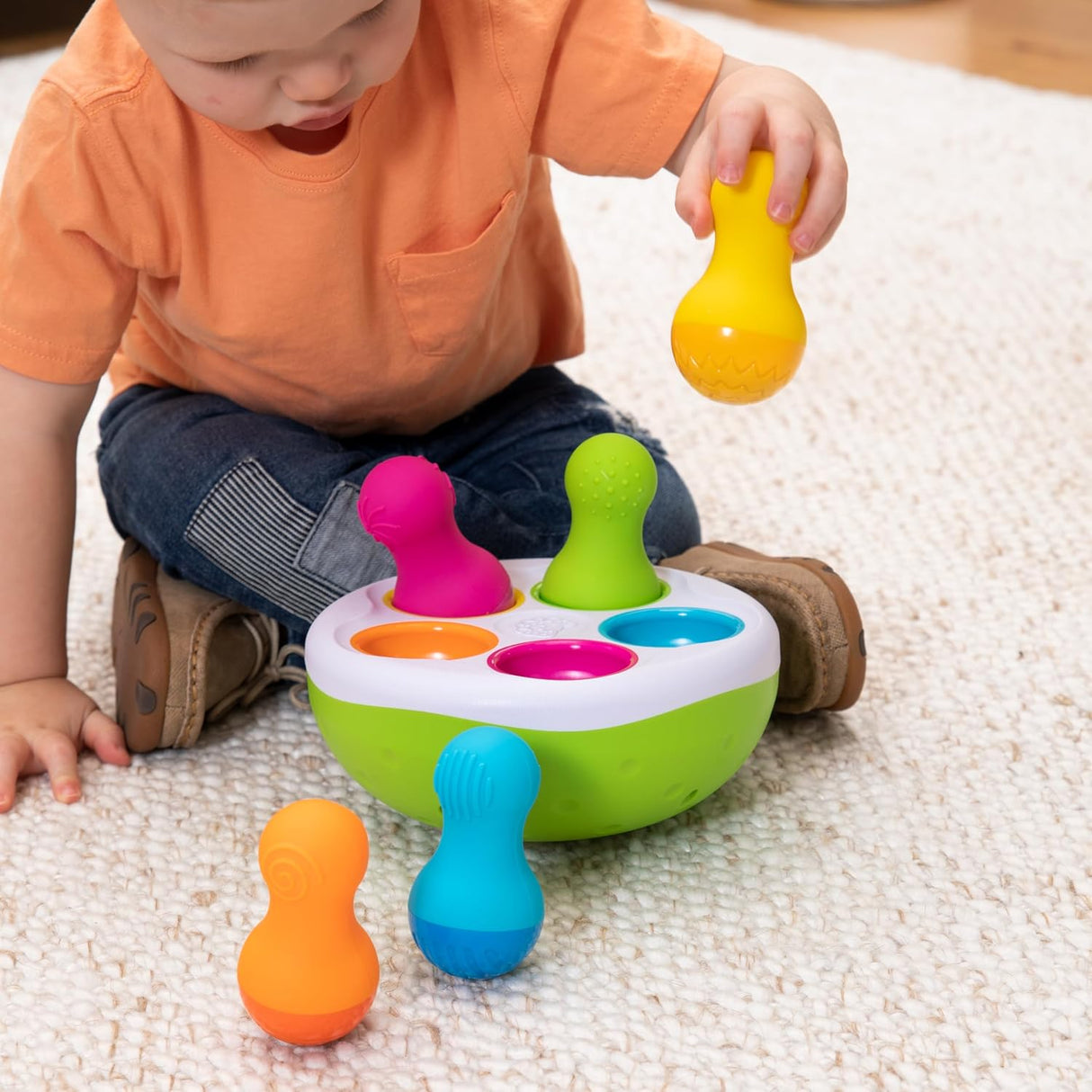 Child playing with SpinnyPins colorful textured wobble pins and bowl for sensory exploration and fine motor skills development.