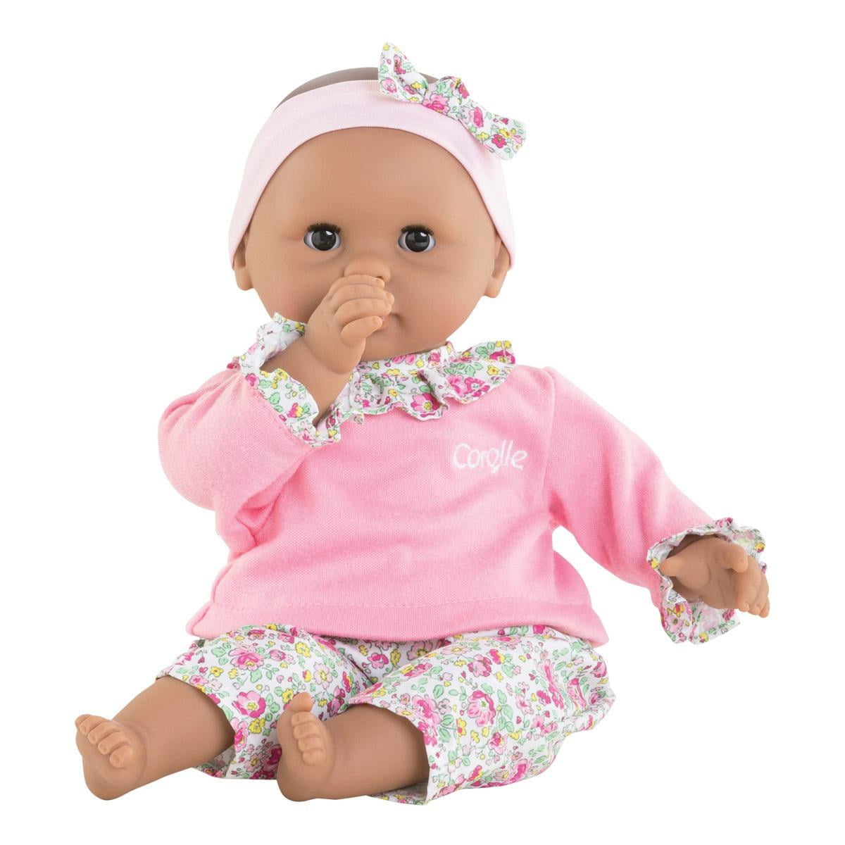 12-inch baby doll with brown eyes wearing pink pajamas and headband, posed sucking thumb and sitting upright