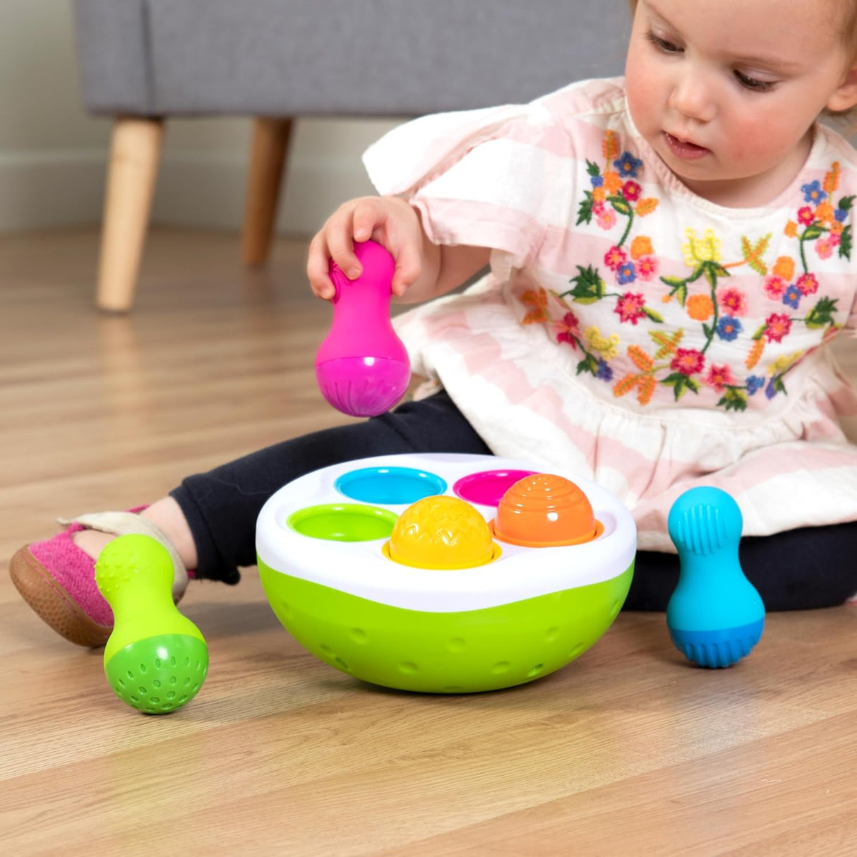 Child playing with colorful SpinnyPins textured, wobbly pins and bowl promoting sensory and motor skills development.