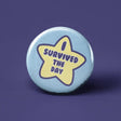 Button I Survived the Day with a yellow star design on a light blue background, measuring 1.25 inches.