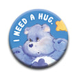 Care Bears Grump Button pin featuring a blue bear with "I need a hug" text on a blue background, 1.25 inch size.