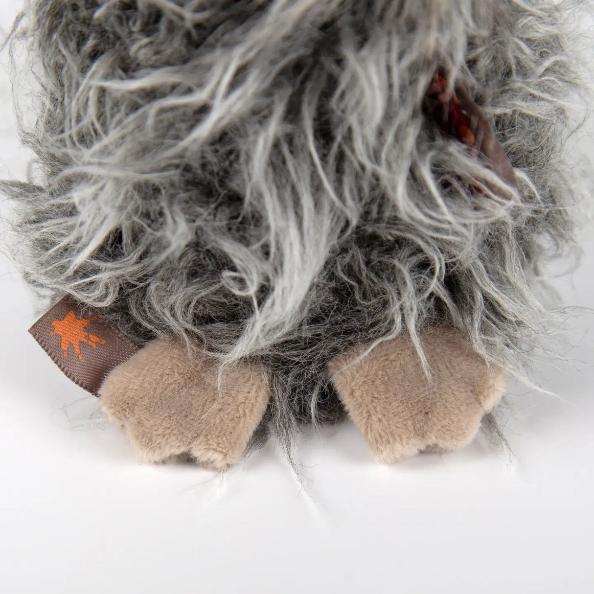 Close-up of soft feet and fluffy fur on the Bird Slow Flyer plush toy with gray and beige colors.