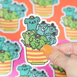 Hand holding Cactus Pups Planter Sticker featuring cute cactus dogs in a striped planter, waterproof vinyl sticker.