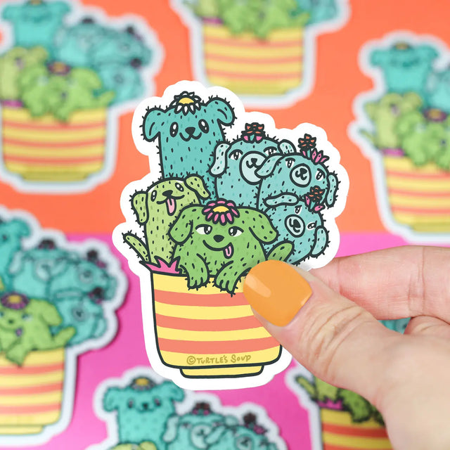 Hand holding Cactus Pups Planter Sticker featuring cute cactus dogs in a striped planter, waterproof vinyl sticker.