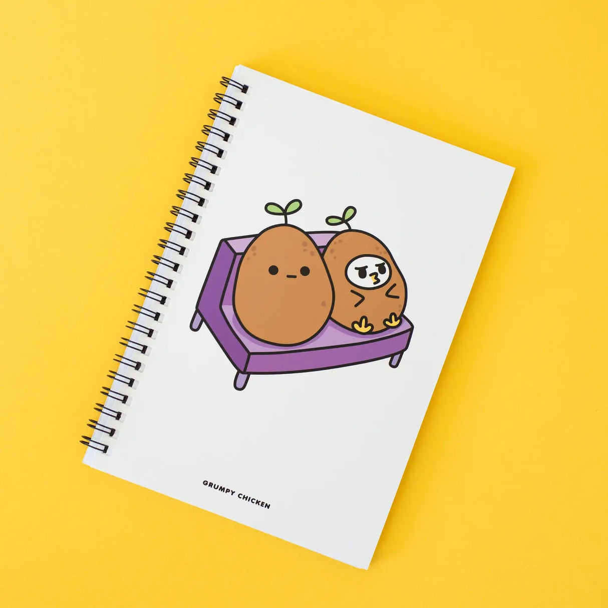 Grumpy Chicken Potato Mode Notebook with spiral binding and cute potato characters on white cover against yellow background