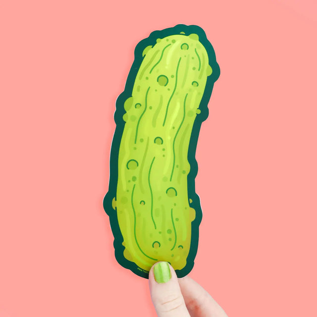 Hand holding a Juicy Dill Pickle Long Sticker with bright green pickle design on pink background.