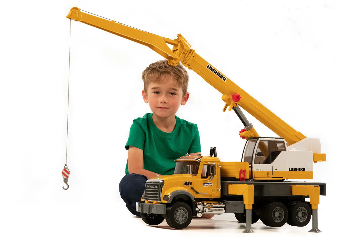 Child playing with MACK Granite Liebherr Crane Truck featuring an extendable boom and realistic details.