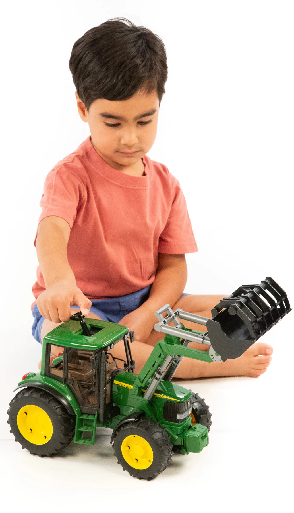 Child playing with John Deere 6920 & Frontloader toy tractor featuring a removable front loader and detailed design.