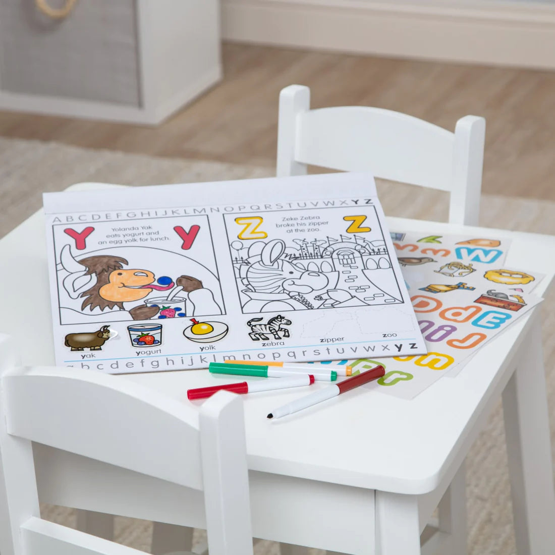Alphabet Activity Pad open on child’s table with coloring pages, markers, and letter stickers for learning alphabets.