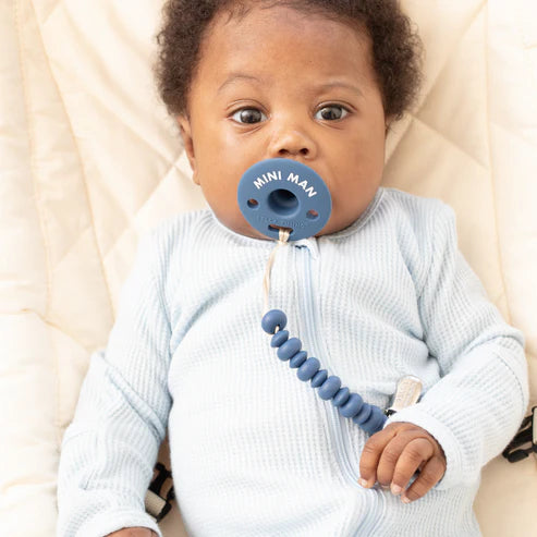 Baby using a blue Pacifier | Mini Man with clip, made of soft, food-grade silicone for comfort and safety.
