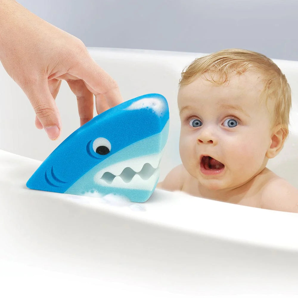 Bath Biters Shark sponge being held near surprised baby in bathtub, adding fun to bath time.