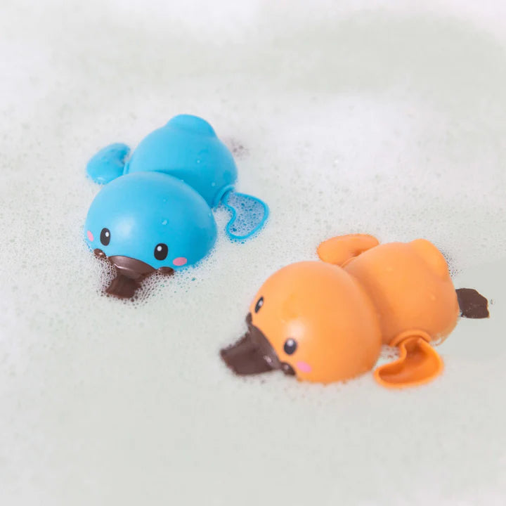 Two bath racer platypuses sitting in soapy bath water- one is orange, the other is blue.