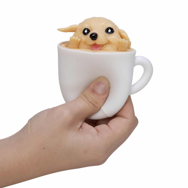 Hand holding a white cup with a squishy pup inside, showcasing the playful Pup in a Cup! product.
