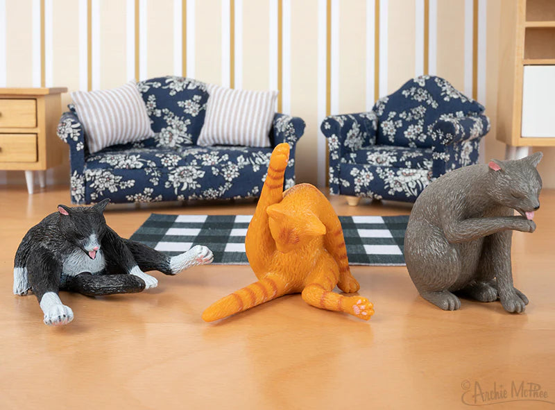 Cleaning Kitty soft vinyl cat figures in three different grooming poses on a wooden floor with mini furniture background.