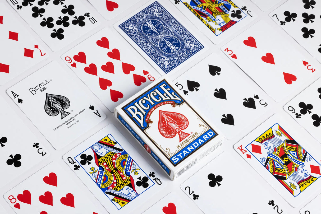 Bicycle Standard Playing Cards deck surrounded by various face and number cards laid out on a white surface.