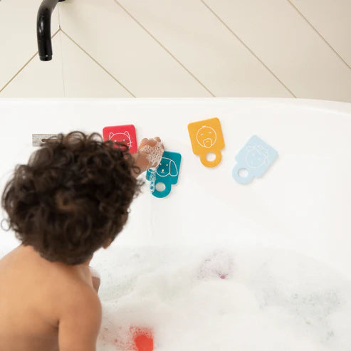 Child playing with Animal Stacker Tub Hub foam flashcards and finger puppets suctioned to bathtub wall.