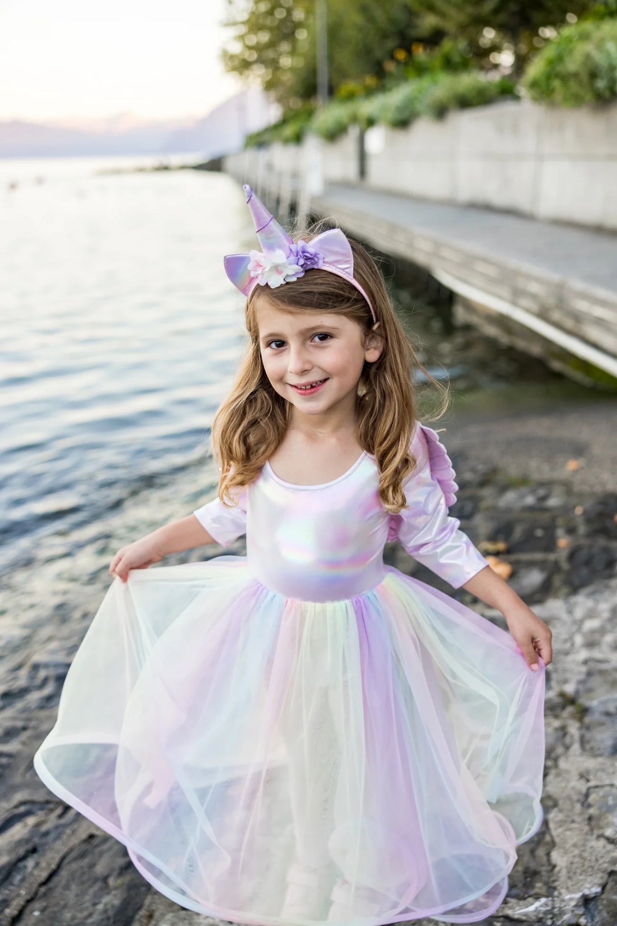 Smiling girl wearing the Alicorn Dress & Wings & Headband with iridescent fabric and flowing tulle skirt outdoors.