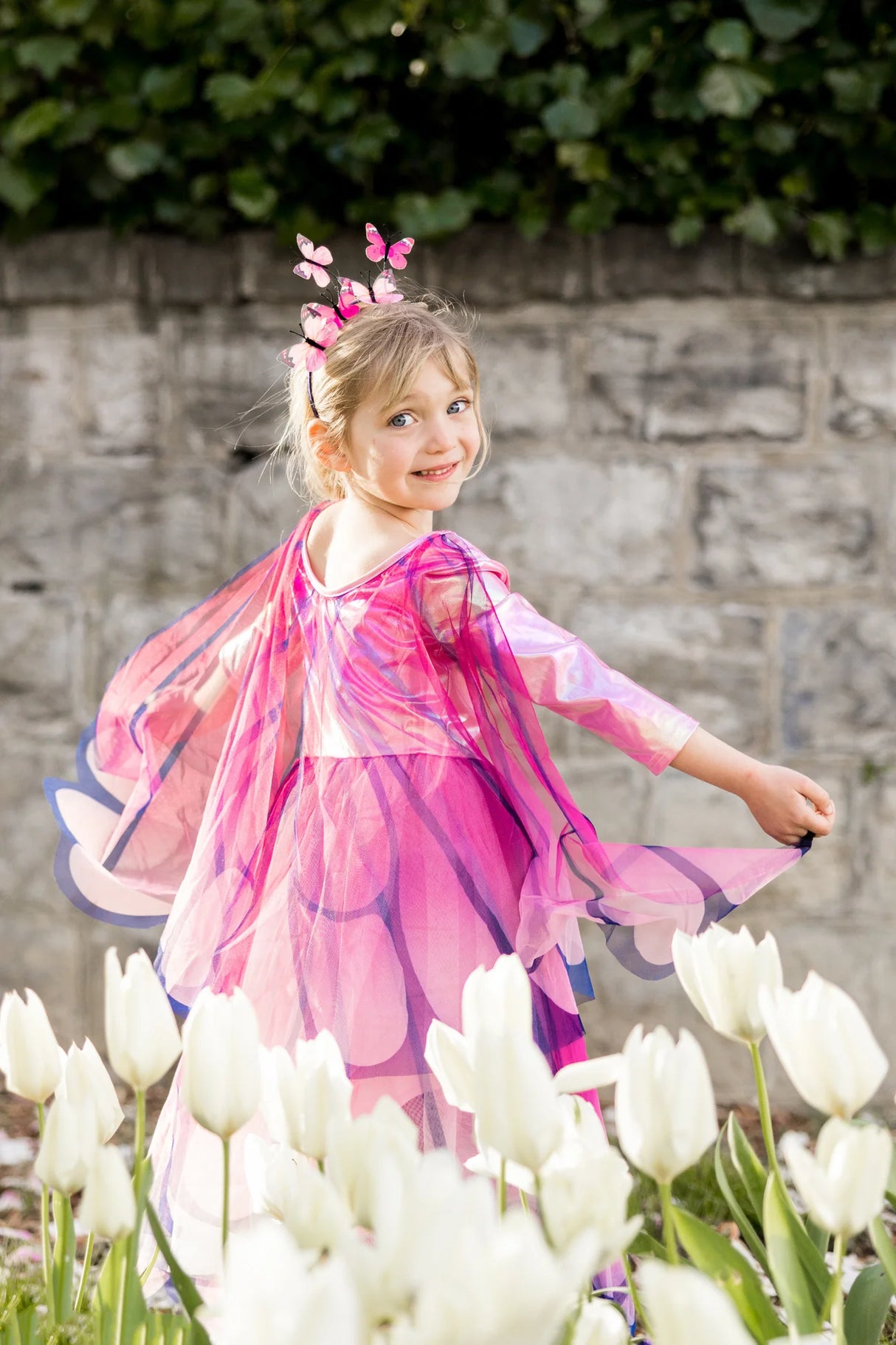 Little girl twirling joyfully in the Butterfly Twirl Dress & Wings | Pink with attached butterfly wings and headband.