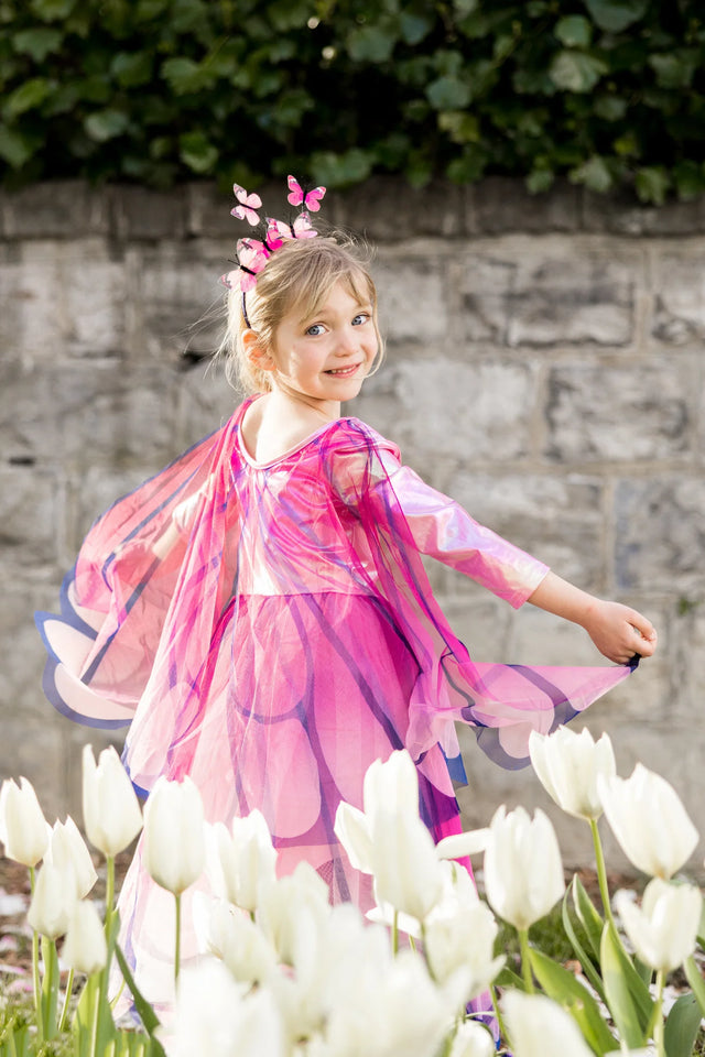 Little girl twirling joyfully in the Butterfly Twirl Dress & Wings | Pink with attached butterfly wings and headband.