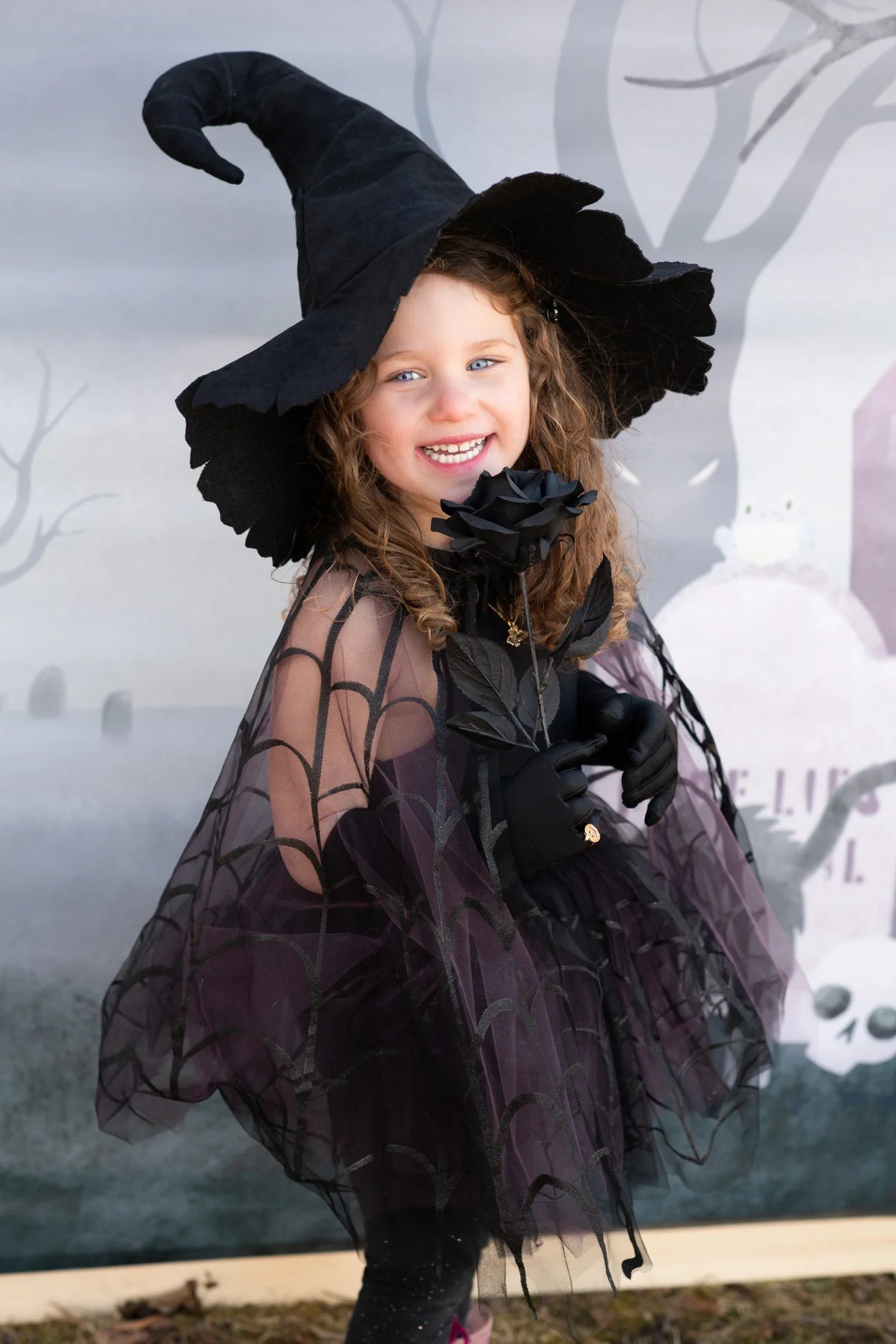 Child wearing Spider Witch Tutu & Cape Size 5-6 with spider web cape and black tutu skirt smiling outdoors.