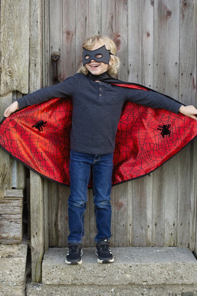 Child wearing Spider Bat Reversible Cape & Mask Size 4-6 showing red spider web satin interior with black spider details.