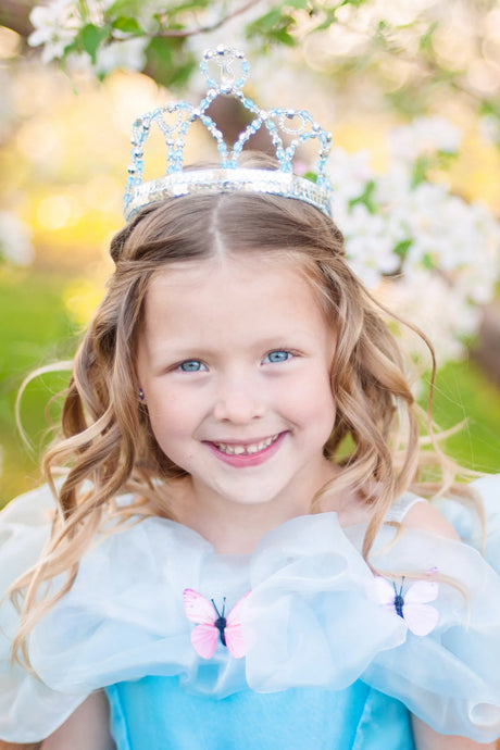 Young girl smiling outdoors wearing a Cinderella Tiara with clear beads and silver sequins accessory