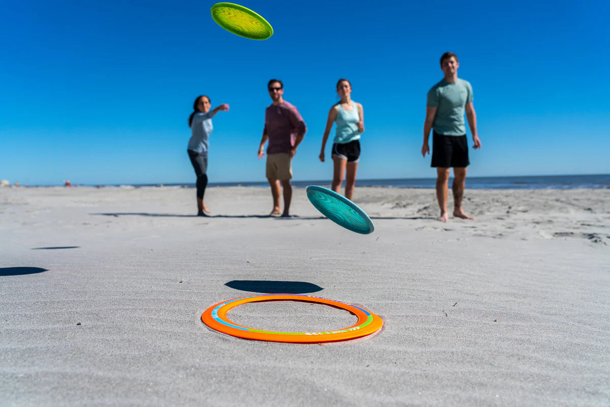 Waboba Backnine game in action on the beach with flying target ring and silicone discs being thrown by players.