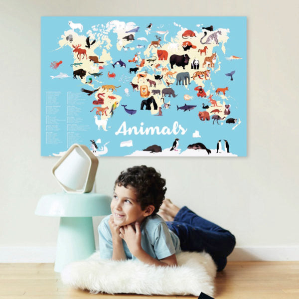 Child lying on floor looking at Poppik Discovery Poster Animals of the World with colorful animal stickers on a map.