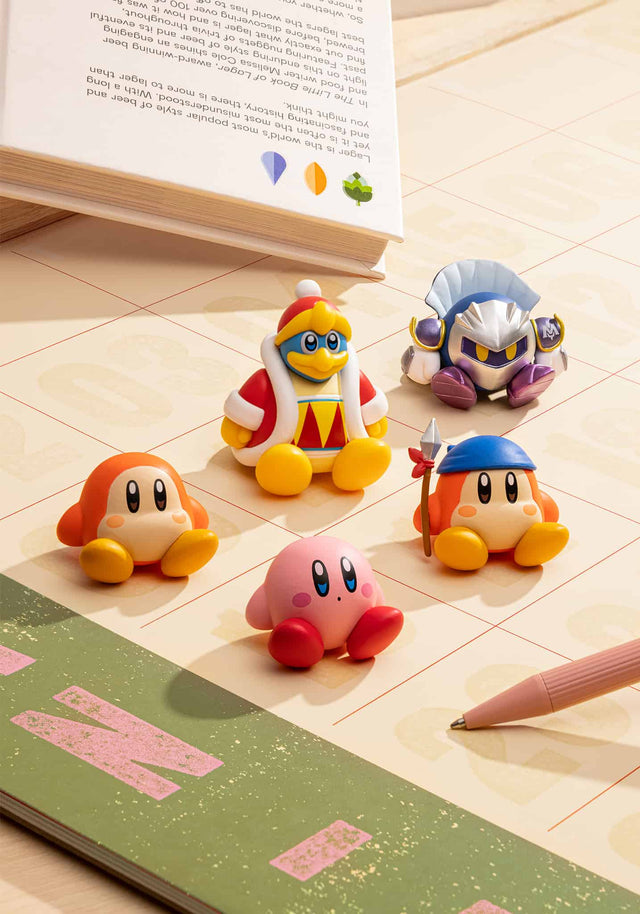 Kirby Sitting Blind Box featuring collectible sitting figures of Kirby and friends on a desk near a book and pen.