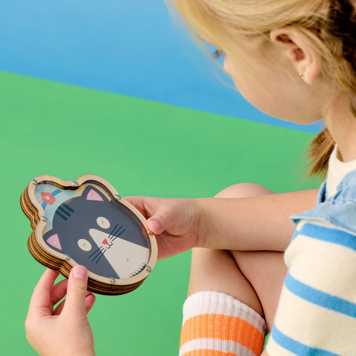 Child playing with a Double Sided Tilt & Roll Puzzle featuring a cute cat design on FSC plywood.