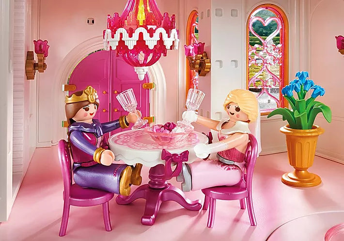 Princess | Castle with queen and princess figures toasting at a pink table under a chandelier inside the elegant castle room.