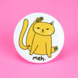 Meh Kitty Cat Button featuring a unimpressed cat grooming itself with "meh" text on a white round pin.