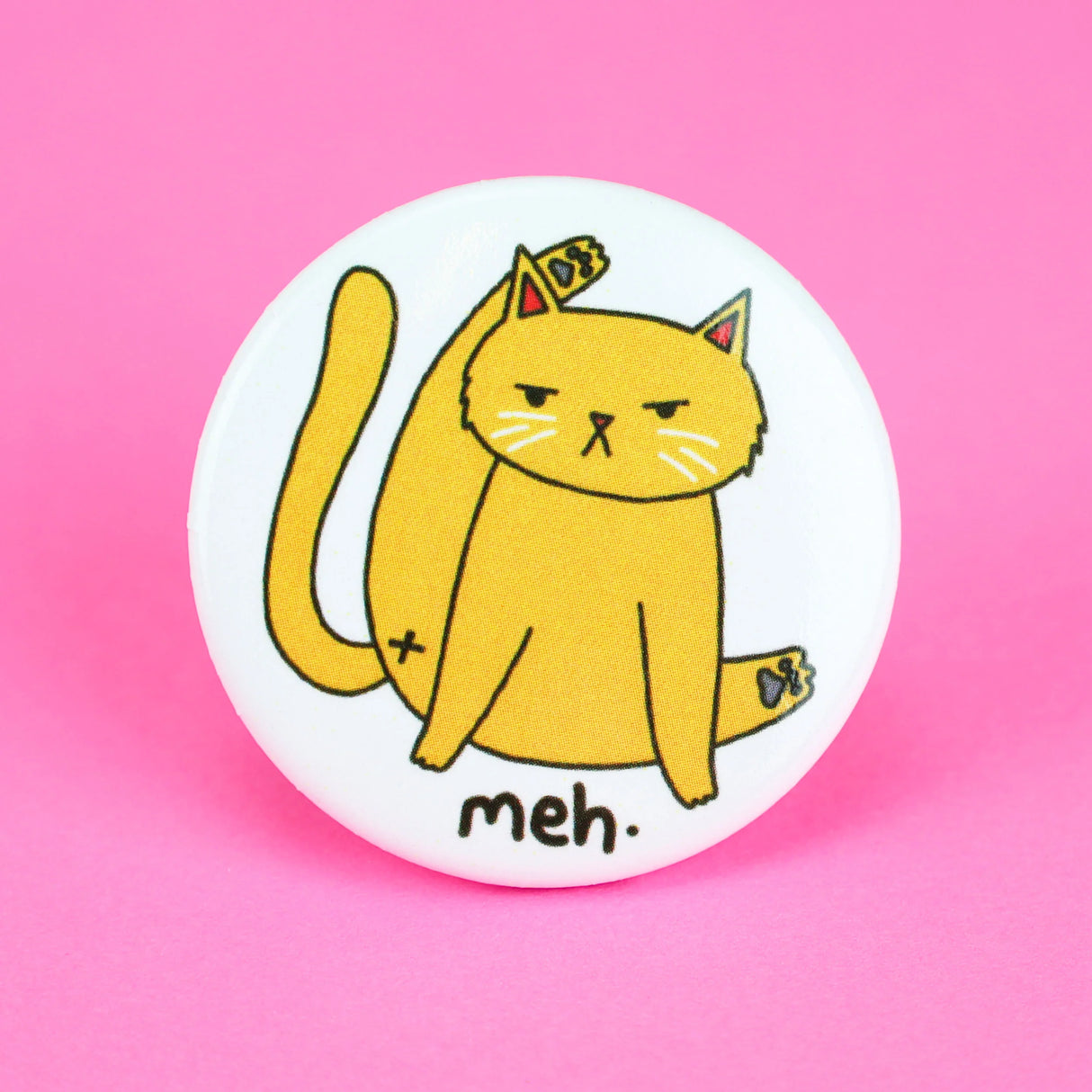 Meh Kitty Cat Button featuring a unimpressed cat grooming itself with "meh" text on a white round pin.