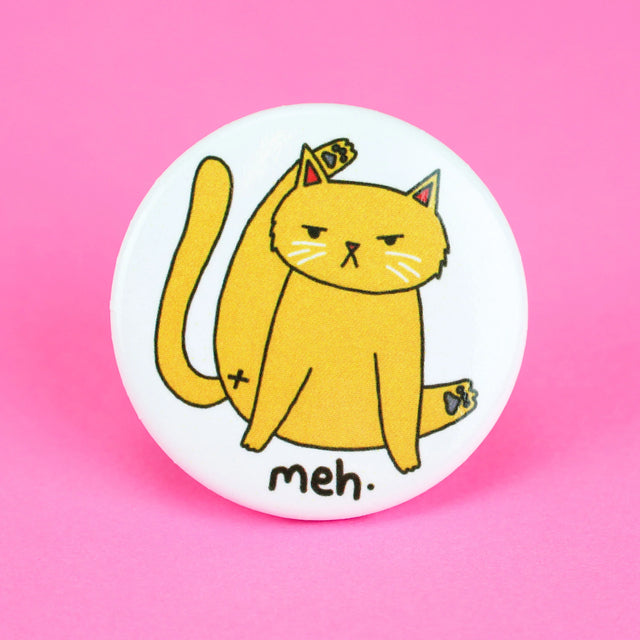 Meh Kitty Cat Button featuring a unimpressed cat grooming itself with "meh" text on a white round pin.