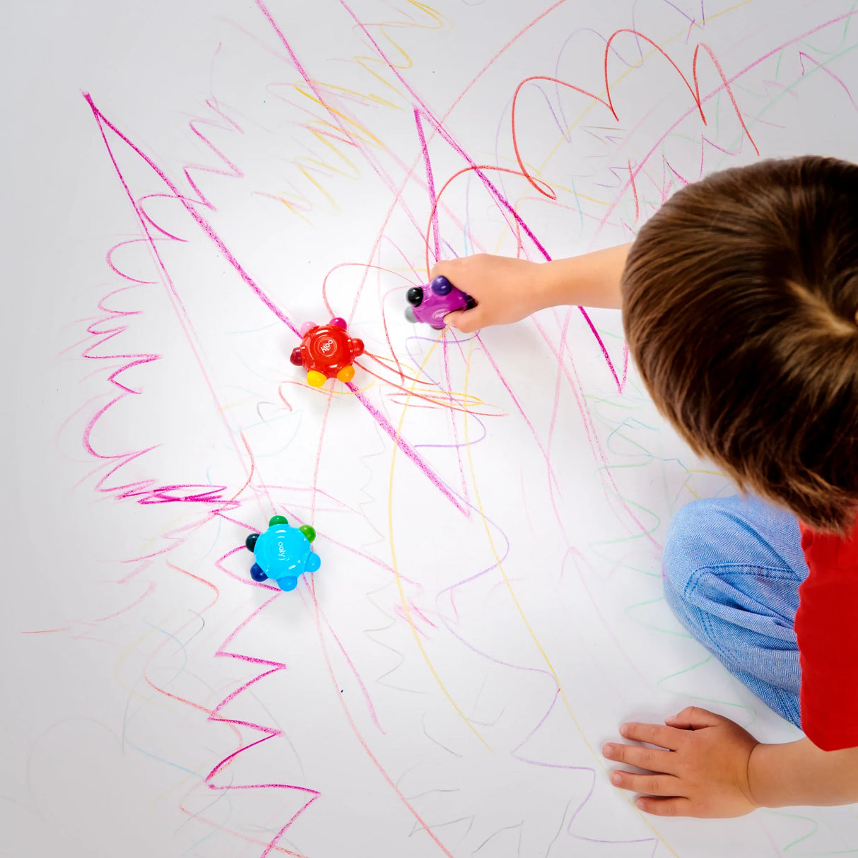 Child drawing colorful scribbles using Color Burst Grip Crayons, showing easy grip and vibrant colors for kids.