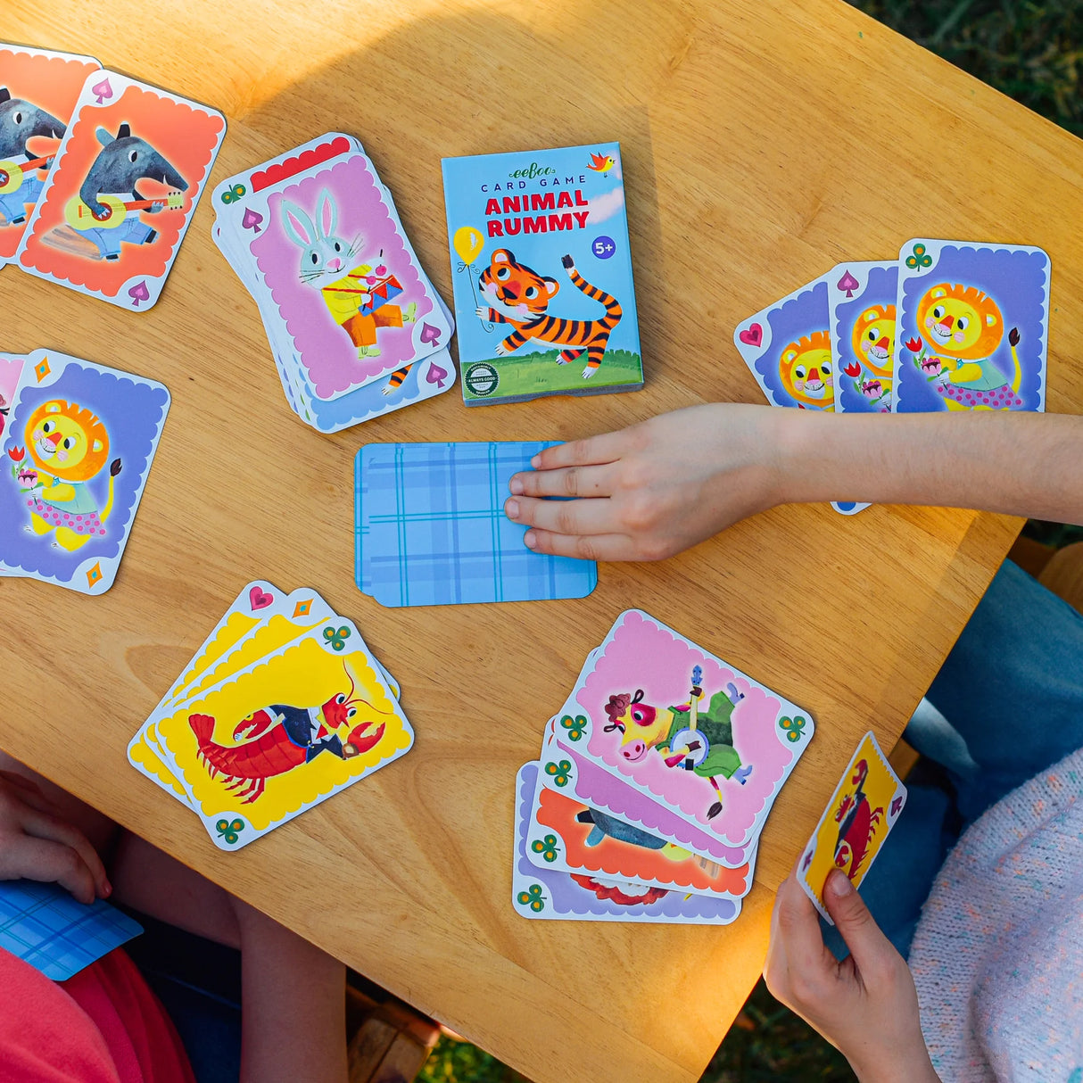 Animal Rummy playing cards with colorful animal illustrations shown on a wooden table during a game.