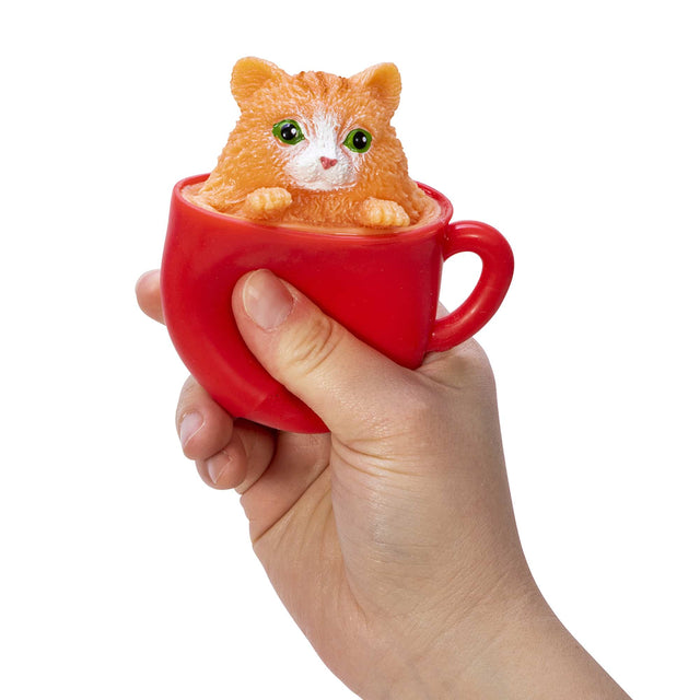 Hand squeezing red cup with orange kitten popping out in Pop a Chino Kitties! collectible toy series.