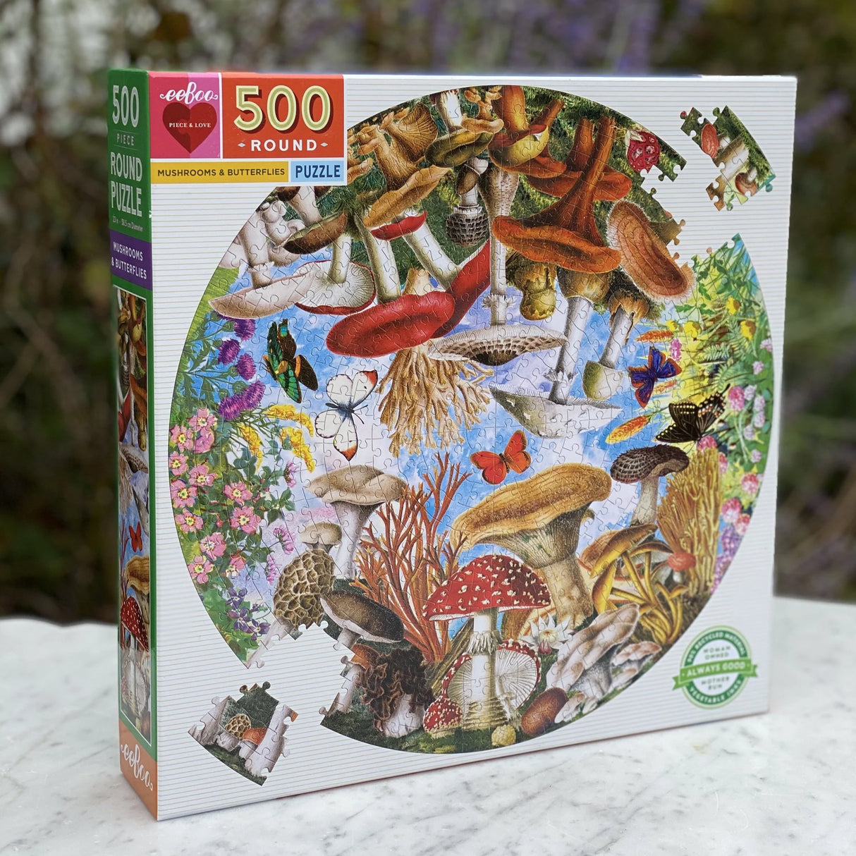 500pc Mushrooms & Butterflies Round Puzzle featuring colorful mushrooms and butterflies in a whimsical garden scene.