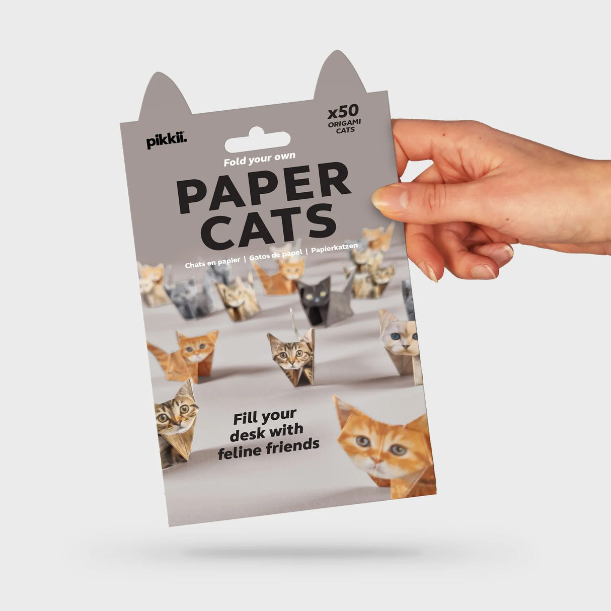 Hand holding a pack of Paper Cats origami kit featuring 50 foldable cat figures on the cover