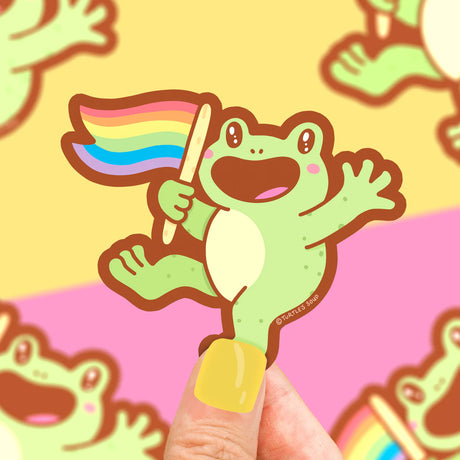 Rainbow Frog Sticker showing a happy green frog holding a waving rainbow pride flag on a colorful background.