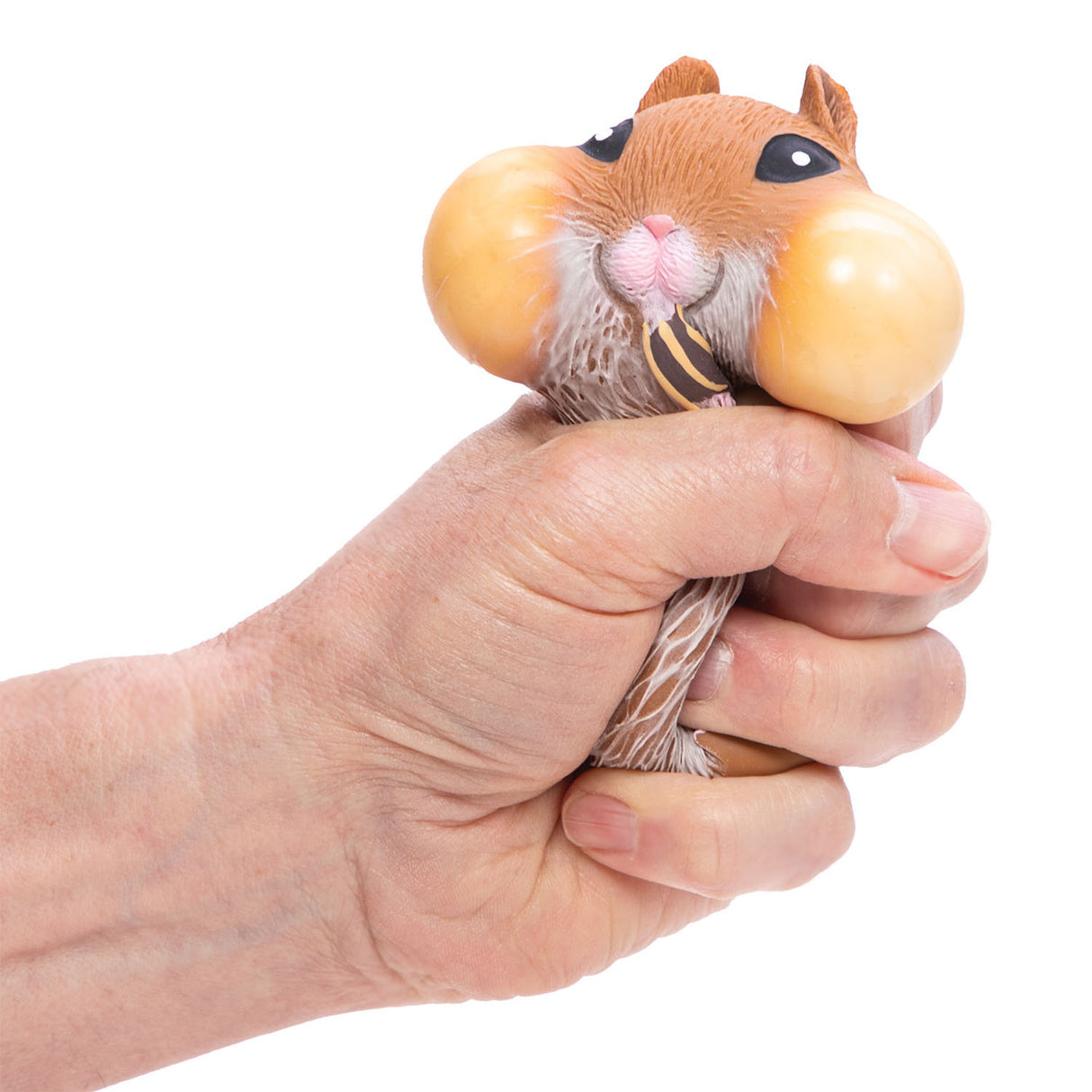Hand squeezing a Chonky Cheeks Hamster toy nibbling on its snack with chubby cheeks in assorted colors.