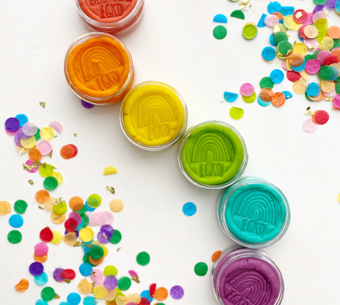 KidDough Mini Rainbow | Bright colorful non-toxic doughs in clear containers surrounded by scattered confetti.