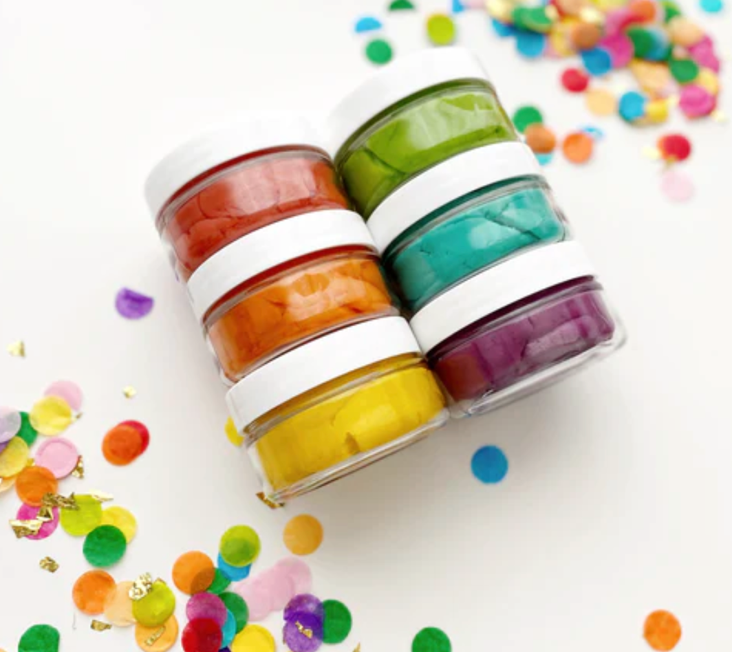 KidDough Mini Rainbow | Bright with six colorful dough containers stacked amid colorful confetti for sensory play.