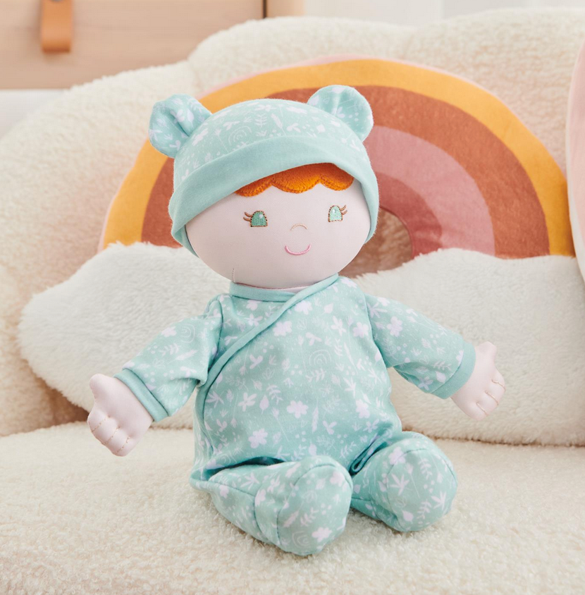 Recycled Baby Doll | Daphnie sitting on cozy chair wearing mint floral onesie with matching hat and embroidered face.
