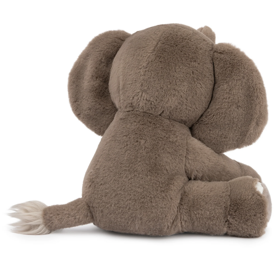 Elephant Chai plush toy sitting upright, showing soft gray fur and a fluffy tail with a white tip.