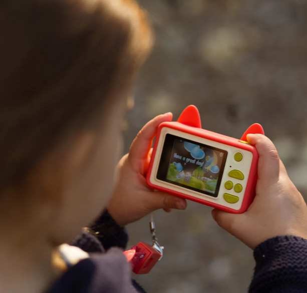 Child holding Digital Camera Model C | Akito the Fox with bright red silicone case and playful screen display.