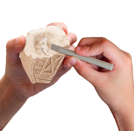 Hands using a tool to uncover a farm animal inside a plaster barn from the I Dig Farm Animals product.