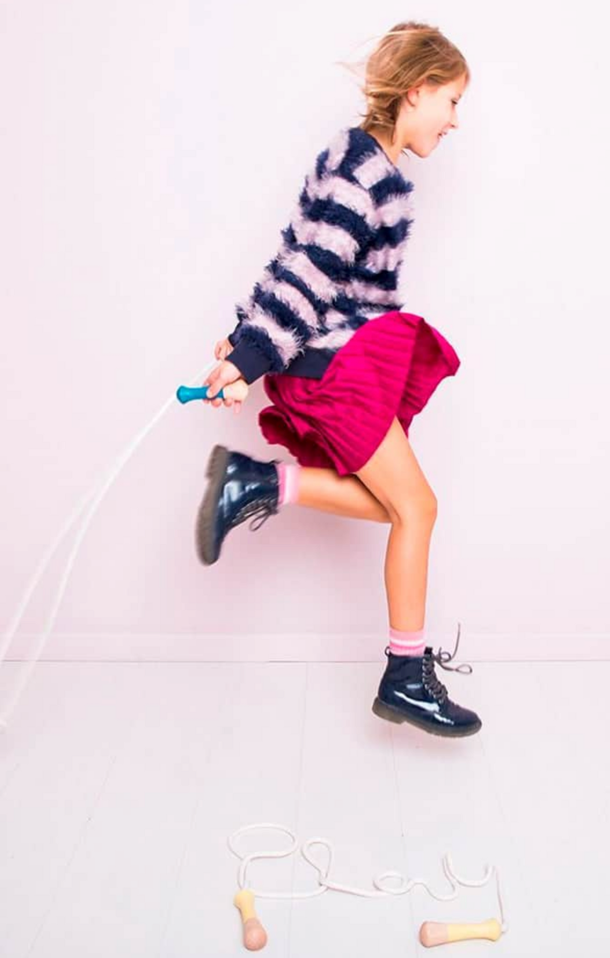 Girl joyfully jumping rope with Jump Rope | Mint, featuring a wooden handle and cotton rope for active play.